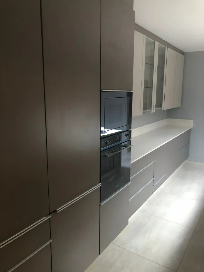 Gray kitchen units with space for microwave and melamine countertops.