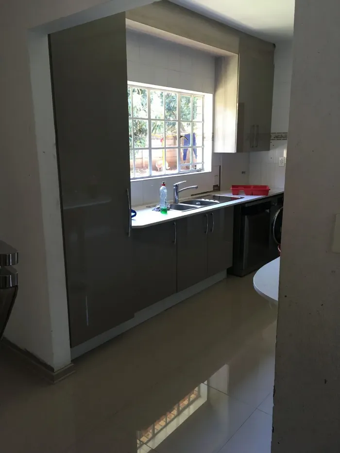 Gray kitchen cabinets with space for microwave and washing machine.