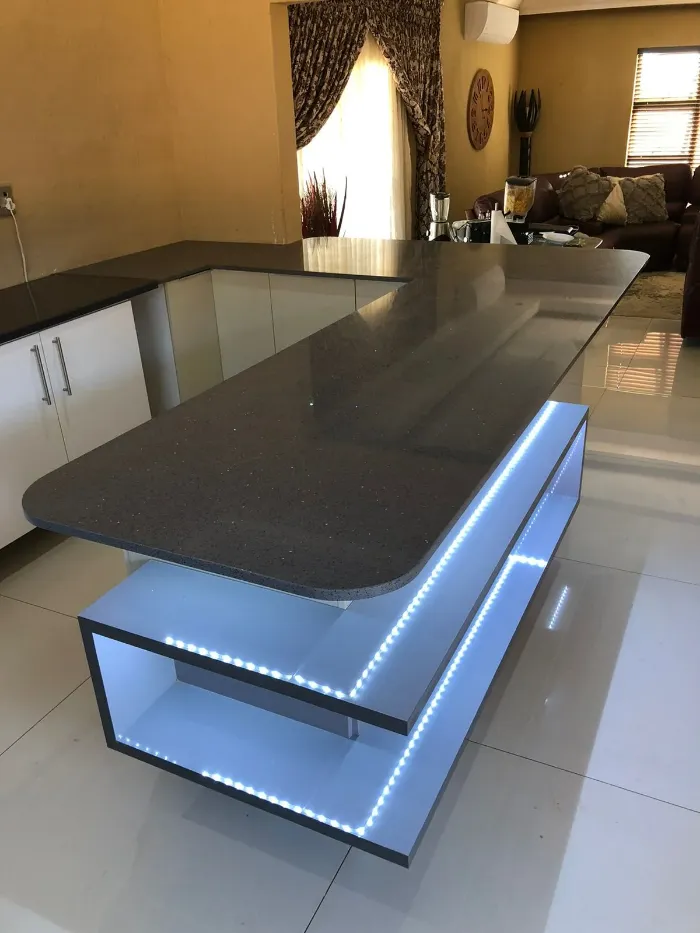 LED-lit kitchen cabinetry with two built-in shelving spaces.
